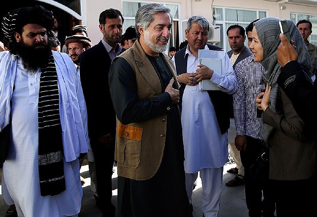 Afghanistan's presidential candidate Abdullah Abdullah, center, is greeted by a supporter after a news conference in Kabul, Afghanistan, Monday, June 23, 2014. Afghanistan's chief electoral officer resigned Monday in a bid to resolve a political crisis over allegations of massive fraud in the runoff presidential vote earlier this month. (AP Photo/Massoud Hossaini)