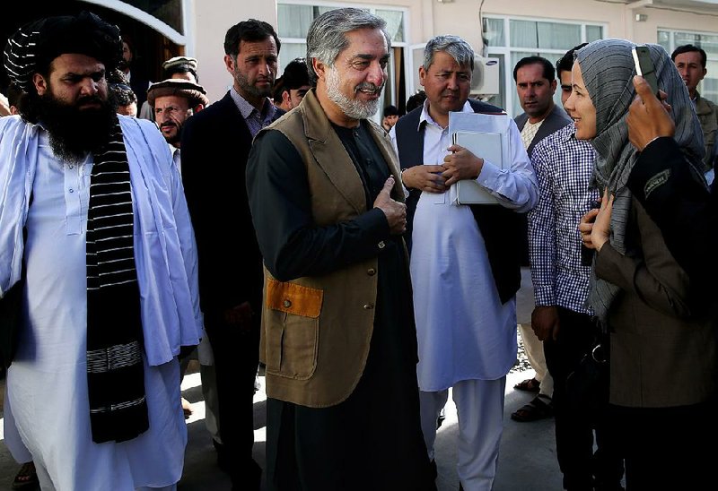 Afghanistan's presidential candidate Abdullah Abdullah, center, is greeted by a supporter after a news conference in Kabul, Afghanistan, Monday, June 23, 2014. Afghanistan's chief electoral officer resigned Monday in a bid to resolve a political crisis over allegations of massive fraud in the runoff presidential vote earlier this month. (AP Photo/Massoud Hossaini)