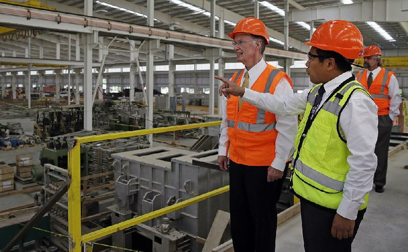 In this Aug. 29, 2013 photo provided by the Alabama Governor's office, Gov. Robert Bentley, left, listens to Roger Zhang, Golden Dragon U.S.A. President, during a tour of the new Golden Dragon copper tubing plant, then under construction, in Pine Hill, Ala. Golden Dragon, the first company Bentley recruited to Alabama after being elected, will employ 300 new full-time employees in rural Wilcox County. (AP Photo/Alabama Governor's Office, Jamie Martin)