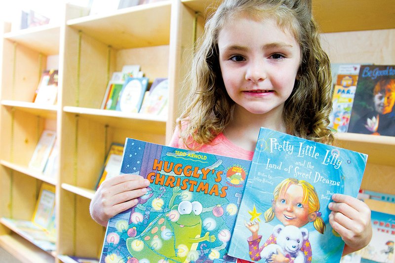 Katie Shirron, 6, holds up two of the books she picked up on a recent trip to the Cabot Summer Reading Bus.