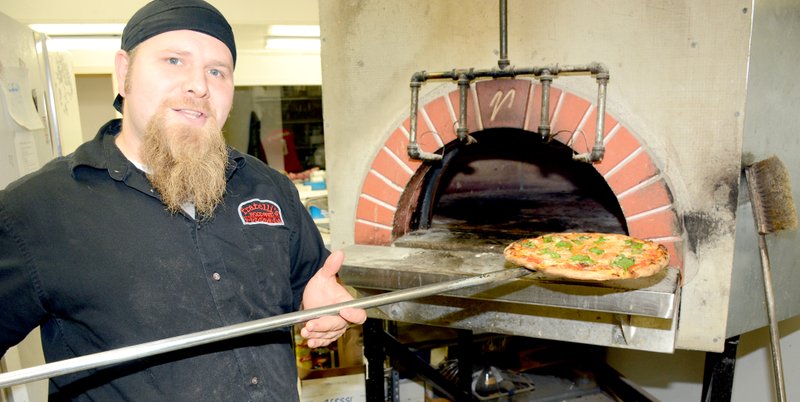 Jeff Della Rosa/Herald-Leader Tom Leadabrand of Fratelli&#8217;s Wood-Fired Pizzeria pulls the Tirol pizza out of the oven.