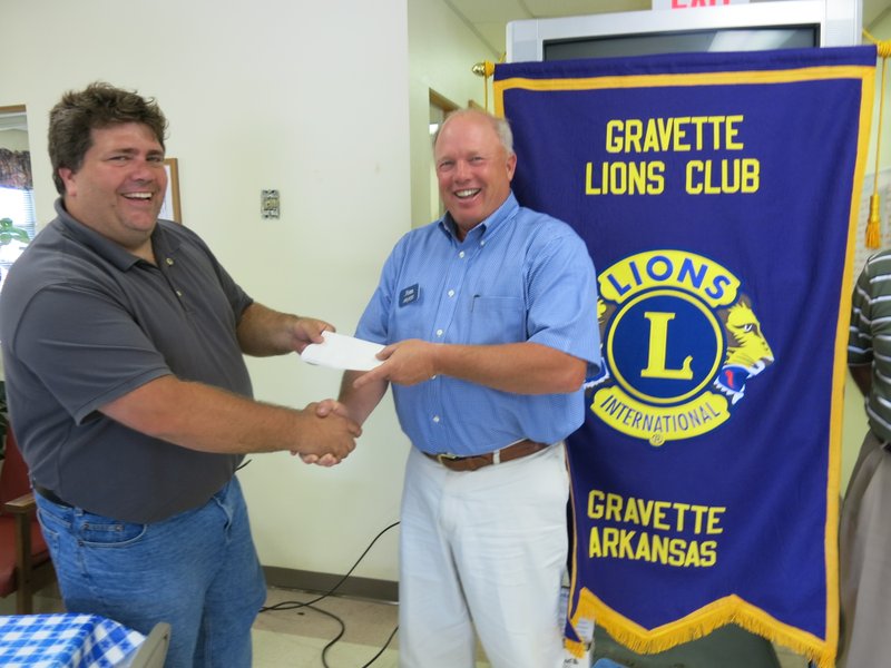 Photo by Susan Holland Gravette Lions Club president Byron Warren, left, accepts a check for $3,000 from Jim Singleton, president of Arvest Bank of Gravette. The $3,000 donation is to help with the construction of the Gravette Heroes Mural project to be located on the wall in front of the Mid-Continent Concrete plant. Construction of the mural is to begin in August, with Gravette High School art students painting the mural panels. The mural should be completed in November 2014. Other donors to the mural project are Teasley Drug, Mid-Continent Concrete and Kenn Foxx & Associates.