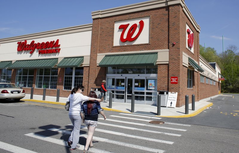In this Wednesday, May 14, 2014 photo, customers walk toward an entrance to a Walgreens store location, in Boston. Walgreen Co. reports quarterly earnings on Tuesday, June 24, 2014.
