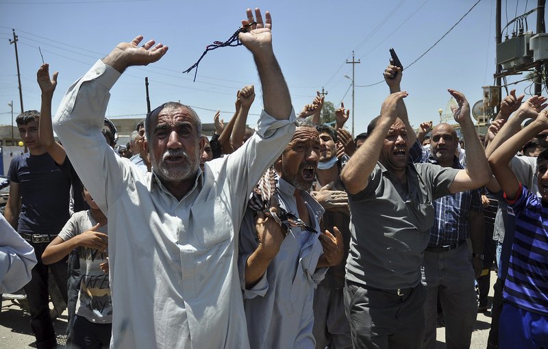 In this June 23, 2014, photo, mourners chant slogans against the al-Qaida breakaway group Islamic State of Iraq and the Levant after they bury 15 bodies in the village of Taza Khormato near the northern oil-rich city of Kirkuk, Iraq. U.S. teams of special forces going into Iraq after a three-year gap will face an aggressive insurgency, a splintering military and a precarious political situation as they help Iraqi security forces improve their ability to battle Sunni militants.