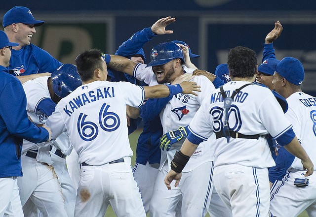 Toronto Blue Jays' Melky Cabrera, center, celebrates with teammates after knocking in the winning run in the Blue Jays 7-6 walk-off win over the New York Yankees during MLB baseball action in Toronto on Tuesday, June 24, 2014. 