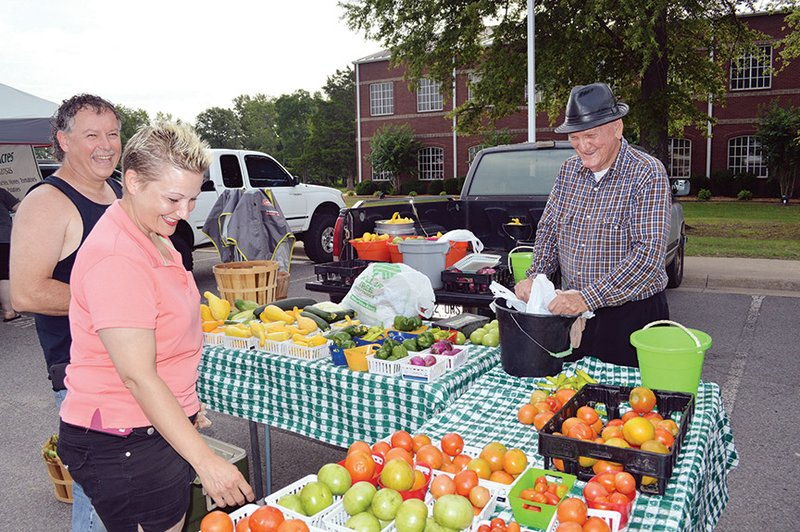 Michelle and Mark Deavers of Conway share a laugh with farmer Jimmy Noland of Conway as they look over his produce at the Conway Farmers Market. The market, which has been operating for about 40 years, is held each Tuesday and Saturday in the Antioch Baptist Church parking lot at 150 Amity Road. 