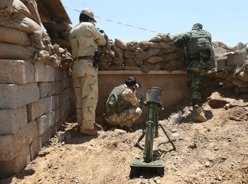 Kurdish peshmerga fighters take their positions behind a wall and sand barriers on the front line with militants from the Islamic State in Iraq and the Levant in Tuz Khormato, 62 miles south of the oil rich province of Kirkuk, northern Iraq, on Wednesday, June 25, 2014. 