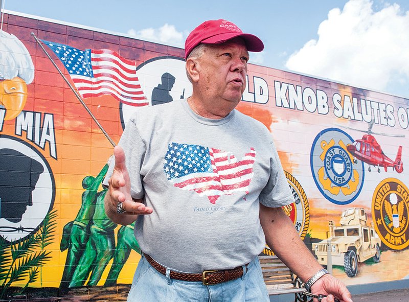 Travis Case talks about plans to do more with the veterans memorial in Bald Knob as he stands in front of a mural that salutes all branches of the service.