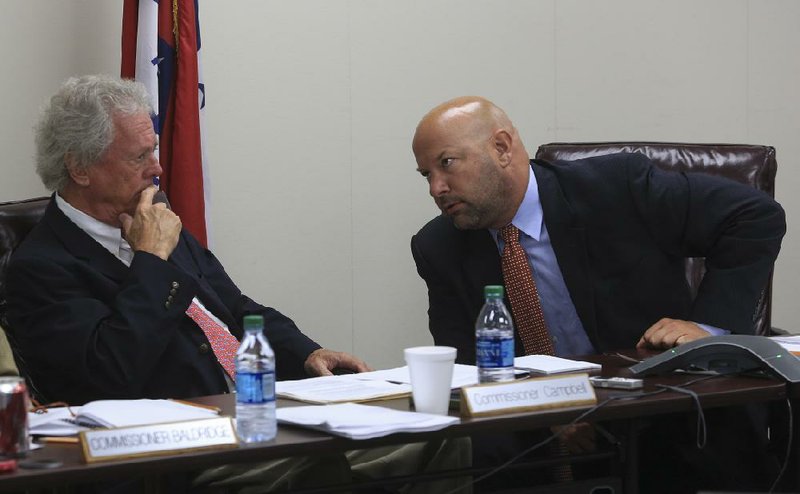 Arkansas Lottery Commission Chairman John “Smokey” Campbell talks with lottery Director Bishop Woosley during a meeting Wednesday. 