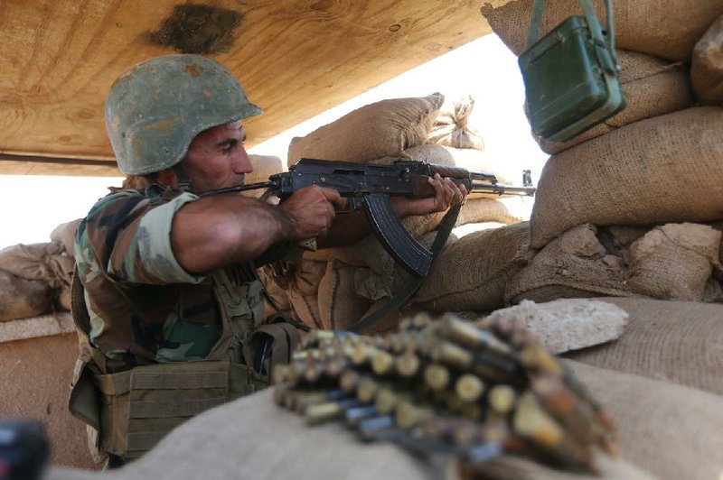 A Kurdish soldier takes aim from his bunker Wednesday on the front lines about 60 miles south of Kirkuk in northern Iraq.
