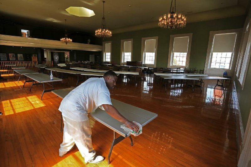 Jermaine Gines cleans tables Wednesday at the Old State House in preparation for the House to convene in the historic chambers during next week’s special session. 