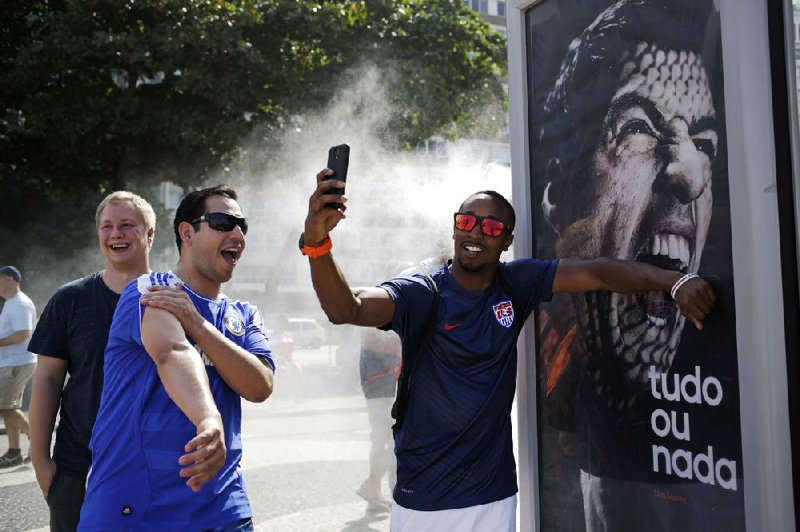 A U.S. soccer fan pretends Uruguay forward Luis Suarez is biting him as he takes a photo Thursday in front of an Adidas advertisement featuring Suarez near Copacabana Beach in Rio de Janeiro. Suarez was banned by FIFA from all soccer for four months and fined $112,000 for biting an Italian player during Uruguay’s 1-0 victory Tuesday.