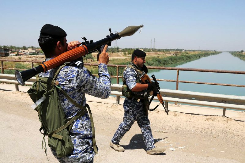 Iraqi federal policemen patrol in the town of Taji, about 12 miles (20 kilometers) north of Baghdad, Iraq, Thursday, June 26, 2014. The Islamic State of Iraq and the Levant (ISIL) took over the country's second largest city 10 days ago. U.S. Secretary of State John Kerry warned Mideast nations on Wednesday against taking new military action in Iraq that might heighten already-tense sectarian divisions, as reports surfaced that Syria launched airstrikes across the border and Iran has been flying surveillance drones over the neighboring country. (AP Photo/Karim Kadim)