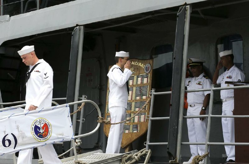 A U.S. Navy sailor, second left, salutes their Philippine counterpart as they disembark from the Philippine frigate BRP Ramon Alcaraz following the opening ceremony of the 20th Cooperation Afloat Readiness And Training (CARAT) joint U.S.-Philippines naval exercise at the former U.S. naval base of Subic, about 70 miles west of Manila, Philippines Thursday, June 26, 2014. After more than a decade of helping fight al-Qaida-linked militants, the United States is disbanding an anti-terror contingent of hundreds of elite American troops in the southern Philippines where armed groups such as the Abu Sayyaf have largely been crippled, officials said Thursday. The move reflects shifting security strategies and focus in economically vibrant Asia, where new concerns such as multiple territorial conflicts involving China have alarmed Washington's allies entangled in the disputes. (AP Photo/Bullit Marquez)