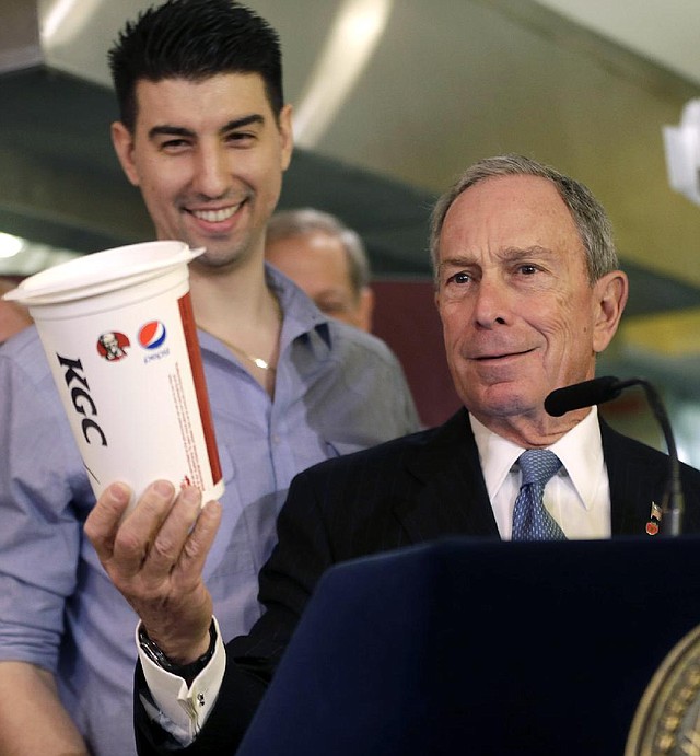 FILE - In this March 12, 2013 file photo, New York City Mayor Michael Bloomberg, right, looks at a 64oz cup, as Lucky's Cafe owner Greg Anagnostopoulos stands behind him, during a news conference at the cafe in New York. The New York Court of Appeals ruled Thursday, June 26, 2014 that the city's health department overstepped its bounds when it restricted the size of sodas. The court is siding with a lower court that overturned the 2012 ban.  (AP Photo/Seth Wenig, File)