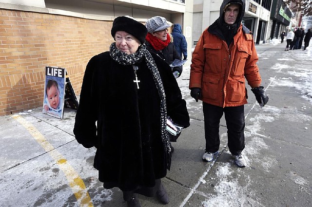 FILE - This  Dec. 17, 2013 file photo shows anti-abortion protester Eleanor McCullen, of Boston, left, standing at the painted edge of a buffer zone as she protests outside a Planned Parenthood location in Boston. In a unanimous ruling Thursday, June 26, 2014, the Supreme Court struck down a 35-foot protest-free zone outside abortion clinics in Massachusetts, saying that extending a buffer zone 35 feet from clinic entrances violates the First Amendment rights of protesters. (AP Photo/Steven Senne, File)