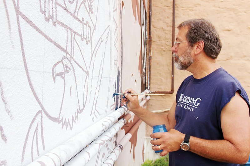 Daniel Adams, professor of art at Harding University, works on a mural honoring veterans on the outside wall of the Zion Climbing Center in downtown Searcy. The mural says “thank you” to veterans for their commitment to the United States.