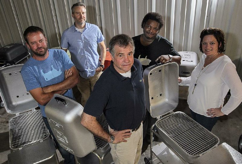 Arkansas Democrat-Gazette/BENJAMIN KRAIN --06/24/14--
Jeff Humiston, left, Scott Moody, back left, and Brian Taylor, not pictured, join Portable Kitchen founders Paul James, center, Martha James, right, and employee Avery Allen, center right, as their new business partners. The grill manufacturing company designs, paints, packages and ships portable charcoal grills from their warehouse in downtown Little Rock.