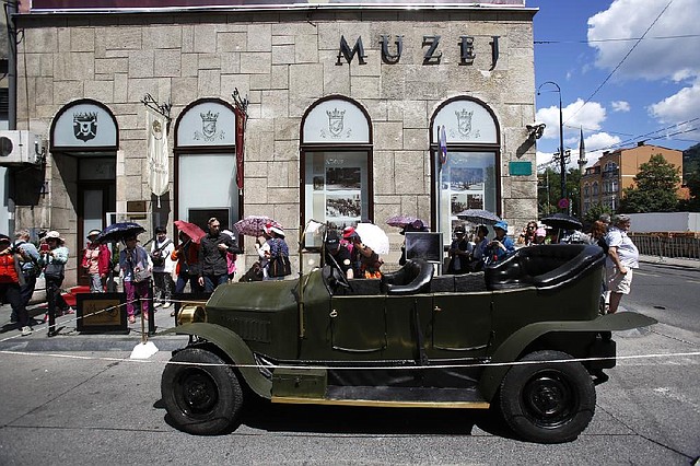Tourists gather on Friday, June 27, 2014, around replica of the "Graf & Stift" car  that Archduke Franz Ferdinand and his wife Sofia rode in as it is parked in front of museum at the historical street corner in downtown Sarajevo, where  Gavrilo Princip, assassinated Austro-Hungarian heir to the throne Archduke Franz Ferdinand and his wife Sofia, on June 28, 1914. The assassination was the event that ignited the start of World War One. (AP Photo/Amel Emric)