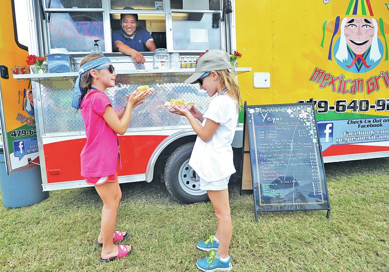 NWA Media/Michael Woods &#8226; @NWAMICHAELW Isabel Iuso, 7, left, and her friend Maya Ellgass, 7, both from Rogers, pick up their nachos Friday while Rafael Rios, owner of the Yeyo&#8217;s Mexican Grill food truck, serves customers from the food truck village set up near the 17th green at the Walmart NW Arkansas Championship Presented by P&amp;G at Pinnacle Country Club in Rogers. Rios usually sets up at a spot in downtown Bentonville but is serving food at the tournament along with other local food trucks.