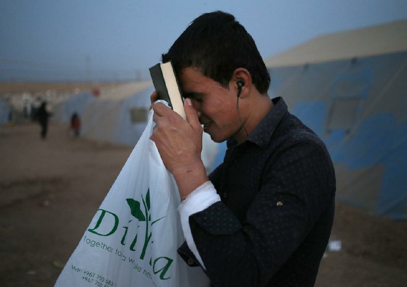 An Iraqi who fled Mosul with his family prays Saturday at a camp outside Irbil. A local Kurdish charity handed out copies of the Koran and carpet squares for the start of the Islamic holy month of Ramadan.
