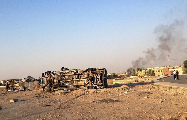 Smoke rises behind a destroyed vehicle Saturday in the northern Iraqi city of Mosul after airstrikes on Islamic forces by the Iraqi military.