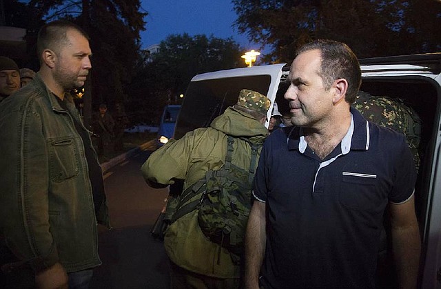 An unidentified member of the OSCE Special Monitoring Mission in Ukraine gets out of a vehicle next to Alexander Borodai, Prime Minister of the self proclaimed 'Donetsk People's Republic', left, on arrival in the city of Donetsk, eastern Ukraine Saturday, June 28, 2014. Four members of the mission were released by officials of the self-proclaimed Donetsk People's Republic after several weeks of captivity. (AP Photo/Dmitry Lovetsky)