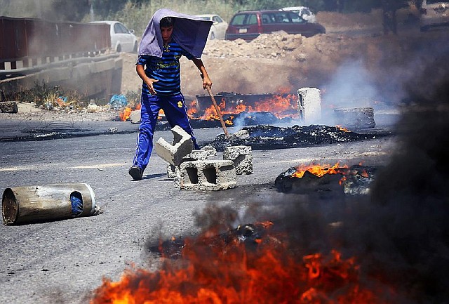An Iraqi Kurd helps block a road during a demonstration against the fuel crisis in Irbil, Iraq, Sunday, June 29, 2014. In Irbil, a city controlled by ethnic Kurds, lines stretched for miles at gas stations for weeks causing demonstrations. (AP Photo)