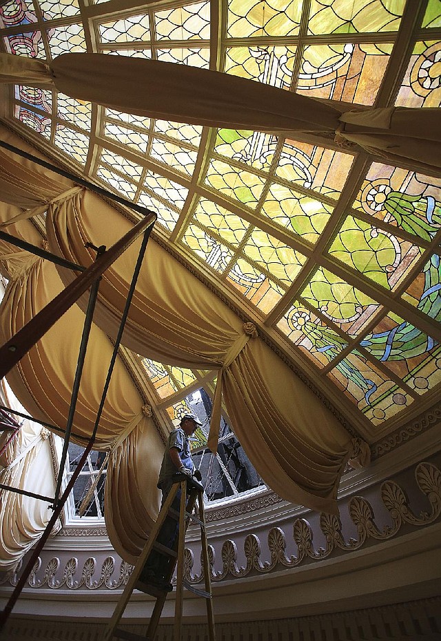  Arkansas Democrat-Gazette/STATON BREIDENTHAL --6/17/14-- Lynn Fitzgerald of Soos Stained Glass in North Little Rock works Tuesday removing stained glass in the dome above the House chamber at the state Capitol. The glass is being removed and will be cleaned and repaired as part of the $1million restoration project of the chamber. 