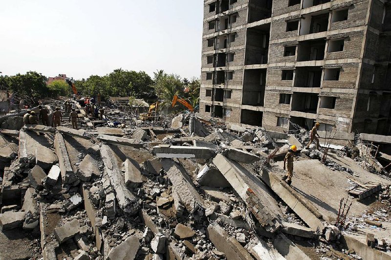 Rescuers search for workers believed buried in the rubble of a building that collapsed on the outskirts of Chennai, India, Sunday, June 29, 2014. The 12-story apartment structure the workers were building collapsed late Saturday while heavy rains and lightning were pounding. Police said 31 construction workers had been pulled out so far and the search was continuing for more than a dozen others. (AP Photo/Arun Sankar K)