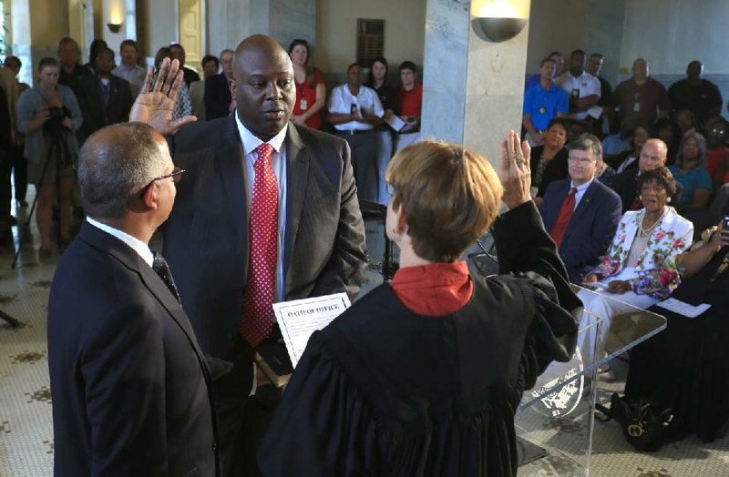 Arkansas Democrat-Gazette/RICK MCFARLAND --06/30/04--    Little Rock City Manager Bruce Moore (left) holds the Bible as Little Rock Police Chief Kenton Buckner takes the oath of office from Judge Alice Lightle at Little Rock City Hall Monday.