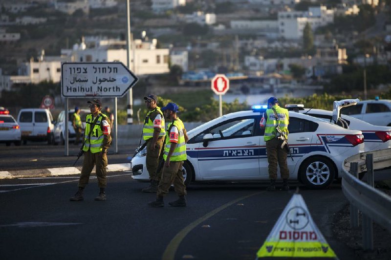 Israeli police officers block a road with their police vehicles in the village of Halhul, near the West Bank town of Hebron, where the bodies of the three missing Israeli teenagers were found, Monday, June 30, 2014. The Israeli military found the bodies of three missing teenagers on Monday, just over two weeks after they were abducted in the West Bank, allegedly by Hamas militants. The grisly discovery culminated a feverish search that led to Israel's largest ground operation in the Palestinian territory in nearly a decade and raised fears of renewed fighting with Hamas.(AP Photo/Majdi Mohammed)