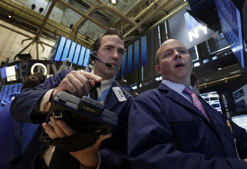 Trader Gregory Rowe, left, and specialist Jason Notter work on the floor of the New York Stock Exchange, Monday, June 30, 2014.  Stocks are narrowly mixed in early trading on Monday. The market is set to end the second quarter with a respectable advance. (AP Photo/Richard Drew)