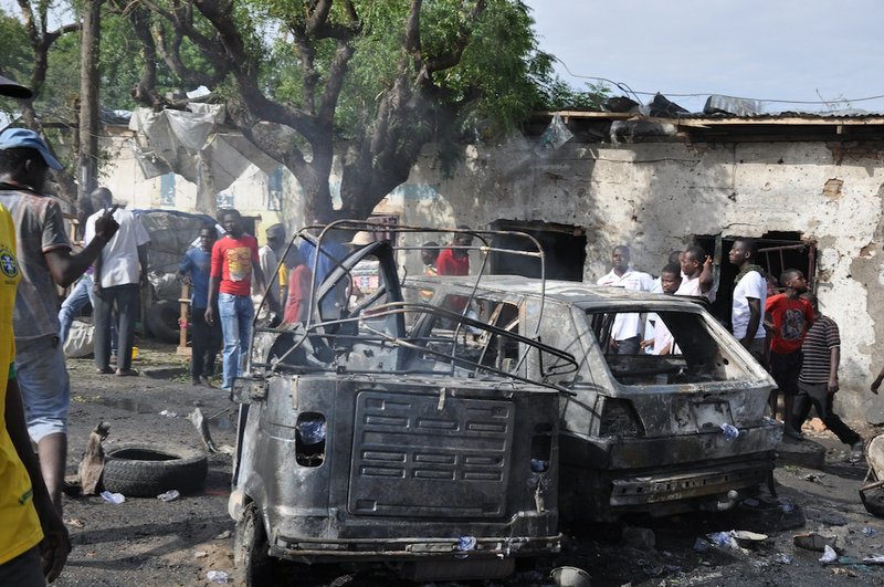 People look at damaged vehicles, at the scene of a car bomb explosion, at the central market, in Maiduguri, Nigeria on Tuesday, July 1, 2014. A car bomb exploded in a market in Nigeria’s northeastern city of Maiduguri on Tuesday morning, and dozens of people are feared dead, witnesses said. 