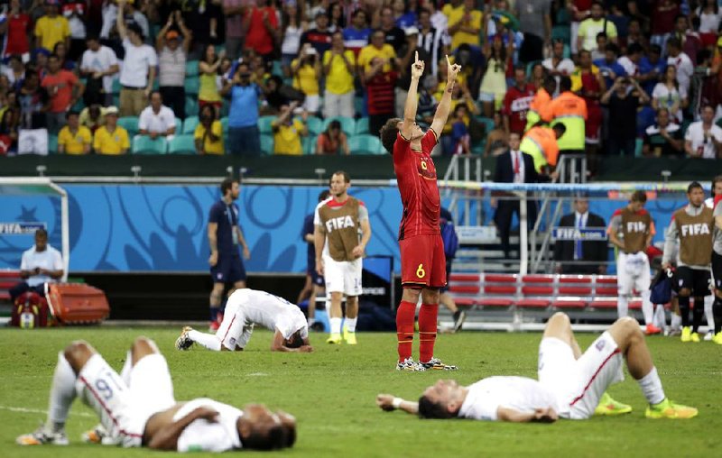 Exhausted American players lie on the ground as Belgium’s Axel Witsel (6) celebrates after a 2-1 World Cup victory in extra time Tuesday at Arena Fonte Nova in Salvador, Brazil. Neither team scored in 90 minutes of regulation play.