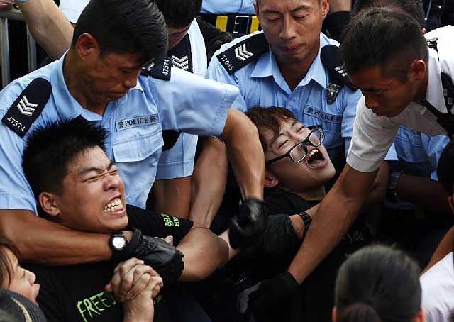 Police officers grapple with protesters today on a street in Hong Kong’s financial district.