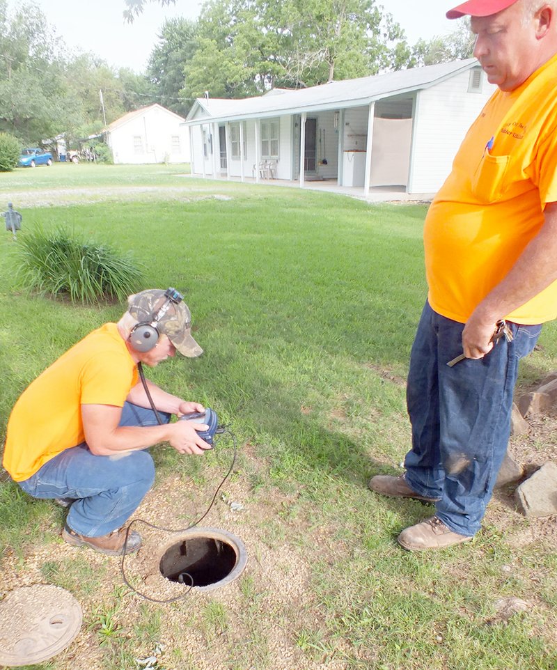 TIMES photograph by Annette Beard Ronnie Hicks and Curtis Wiltgen of the Pea Ridge Water Department listen for leaks in water lines. The two have fine-tuned the skill and are excellent at finding water leaks, according to Ken Hayes, superintendent.