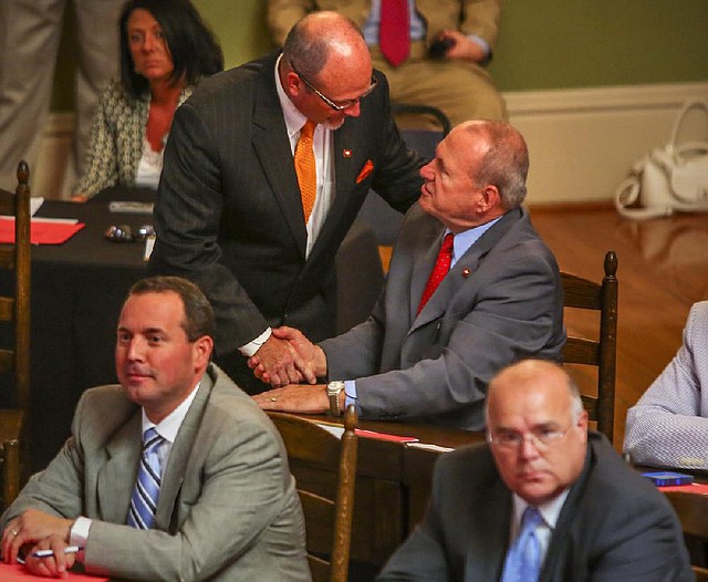 Rep. Harold Copenhaver (top center), D-Jonesboro, is congratulated Tuesday by Rep. Mike Holcomb, D-Pine Bluff, after his bill on funding for public school employee health insurance was approved.