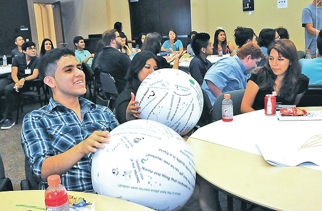 STAFF PHOTO FLIP PUTTHOFF Eduardo Martinez, left, and Eva Jauregui, take part in an exercise Tuesday involving questions written on beach balls during the Learning, Improvement, Fun and Empowerment program at NorthWest Arkansas Community College in Bentonville.