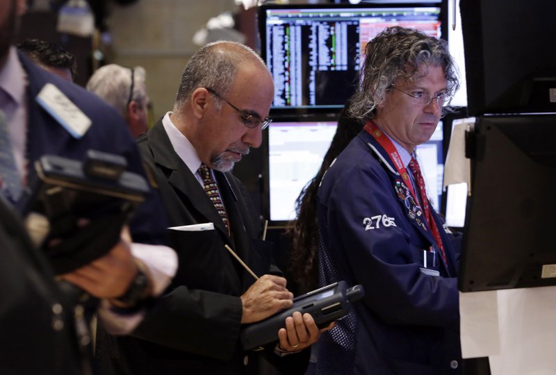 In this Monday, June 30, 2014 photo, trader John Liotti, center, and specialist Donald Civitanova, right, work on the floor of the New York Stock Exchange. World stocks were mostly higher Wednesday, July 2, 2014, on improved U.S. and Chinese economic activity.