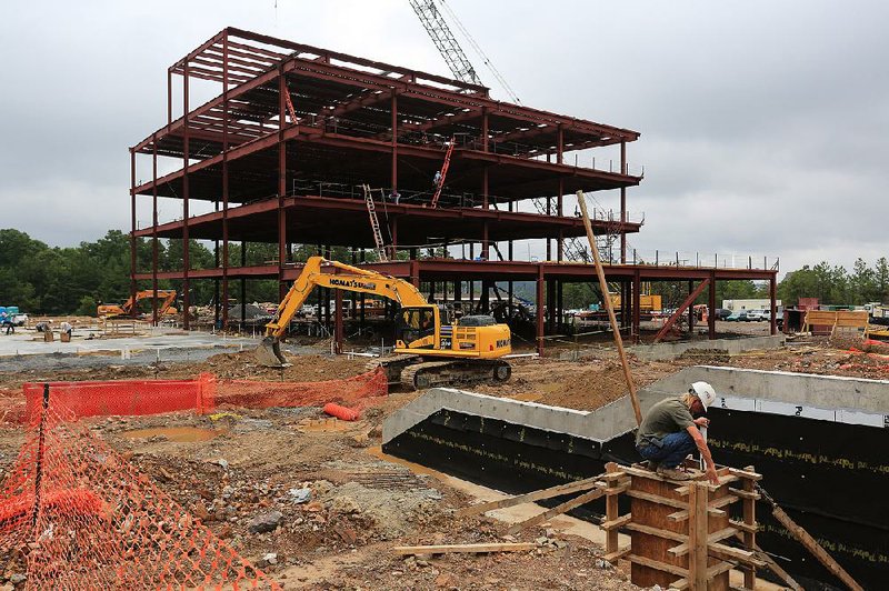 A construction worker (right) prepares a form last month at the site of the Central Arkansas Radiation Therapy Institute Cancer Center, set to open in fall 2015. Work at the site is being managed by Colliers International and Flake & Kelley Commercial.