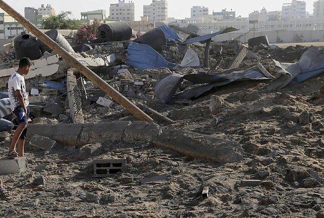 A Palestinian checks the damages of a Hamas training camp following an Israeli air strike on it early morning in Gaza City Thursday, July 3, 2014. Israeli military carried out airstrikes on the Gaza Strip after Palestinian militants fired rockets into Israel early Thursday. The Israeli military said the air force struck 15 "terror sites" in Gaza. "The targets included weapons manufacturing sites as well as training facilities," a military spokesman said. (AP Photo/Adel Hana)