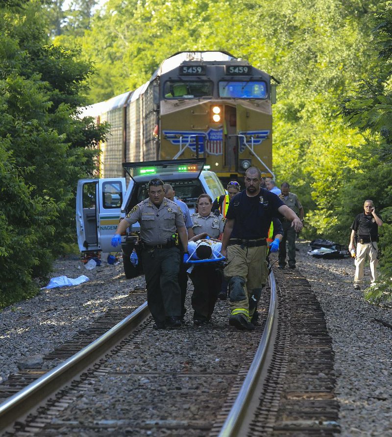  Arkansas Democrat-Gazette/STATON BREIDENTHAL --7/3/14-- Emergency personnel carry one of three people injured in an accident involving a car and a train to a waiting ambulance Thursday morning near Sweet Home. One person died in the accident Pulaski County sheriff’s office spokesman Lt. Carl Minden said. 