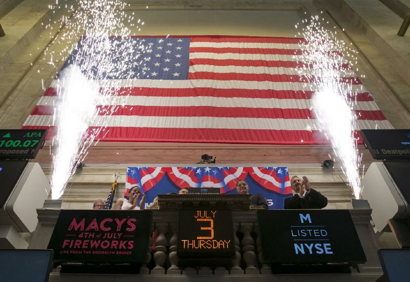 Fireworks frame representatives of Macy’s as they ring the closing bell of the New York Stock Exchange on Thursday. The Dow Jones industrial average jumped above 17,000 for the first time after the government reported a surge in hiring last month that was much bigger than investors and economists were expecting.