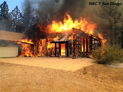 In this still frame from video provided by KNSD-TV, a home is fully involved in flames as crews scrambled to corral a wildfire that burned two homes near the San Diego County mountain town of Julian in Southern California Thursday, July 3, 2014. The blaze erupted around 10:30 a.m. and prompted the mandatory evacuation of 200 homes. Firefighters attacked the 150-acre blaze in the air and on the ground. The fire destroyed two homes and an outbuilding and was 15 percent contained at nightfall, state fire Capt. Kendal Bortisser said.