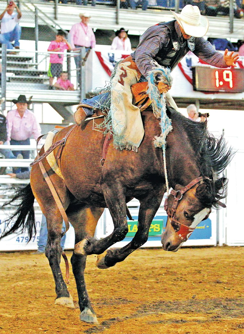  STAFF PHOTO JASON IVESTER Louie Brunson of Interior, S.D., competes in the saddle bronc riding on Thursday during the Rodeo of the Ozarks at Parsons Stadium in Springdale.