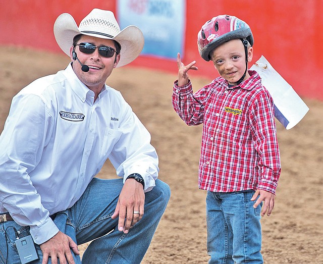 STAFF PHOTO ANTHONY REYES Announcer Joe Rollins, left, talks with Logan Carter after he fell off a sheep Wednesday during the Rodeo of the Ozarks at Parsons Stadium in Springdale.