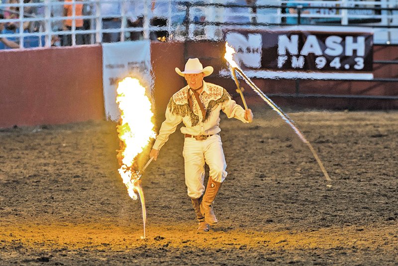  STAFF PHOTO ANTHONY REYES Rider Kiesner slings flaming whips Wednesday during the Rodeo of the Ozarks at Parsons Stadium in Springdale. Kiesner showed the audience tricks with lasso, whips and a six shooter.