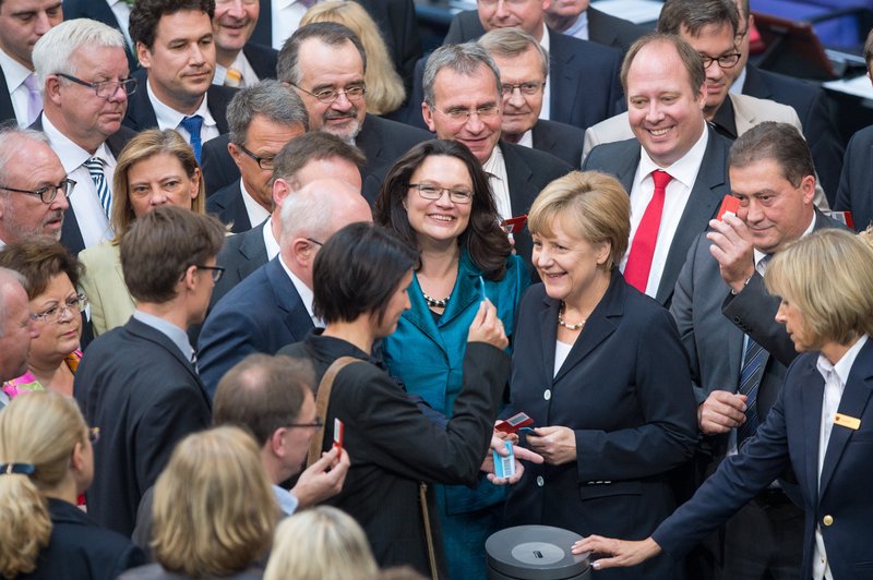 German chancellor  Angela Merkel, center right,  stands next to  labor minister Andrea Nahles,  center left, as they are surrounded by parliamentarians casting  their vote  in the German parliament, Bundestag, in Berlin Thursday July 3, 2014. The German Parliament has approved the introduction of the country's first national minimum wage, which will guarantee most workers in Europe's biggest economy at least 8.50 euros (US $11.60) per hour starting next year.