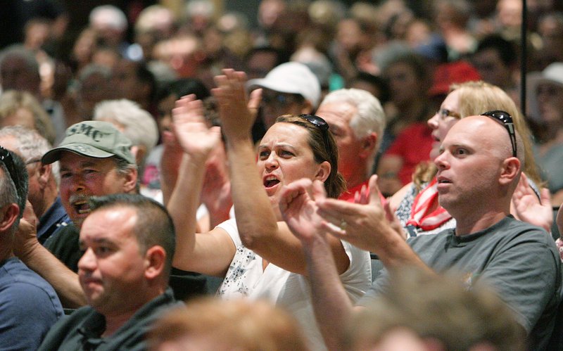 Attendees cheer as Riverside County Supervisor Jeff Stone speaks during a meeting about a plan to process immigrants detained in Texas at the Murrieta U.S. Border Patrol facility, during a meeting at the Murrieta Mesa High School auditorium Wednesday, July 2, 2014, in Murrieta, Calif.